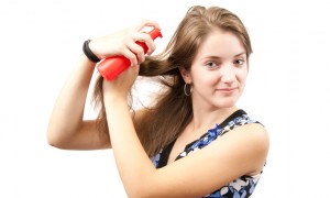 girl spraying hair over white